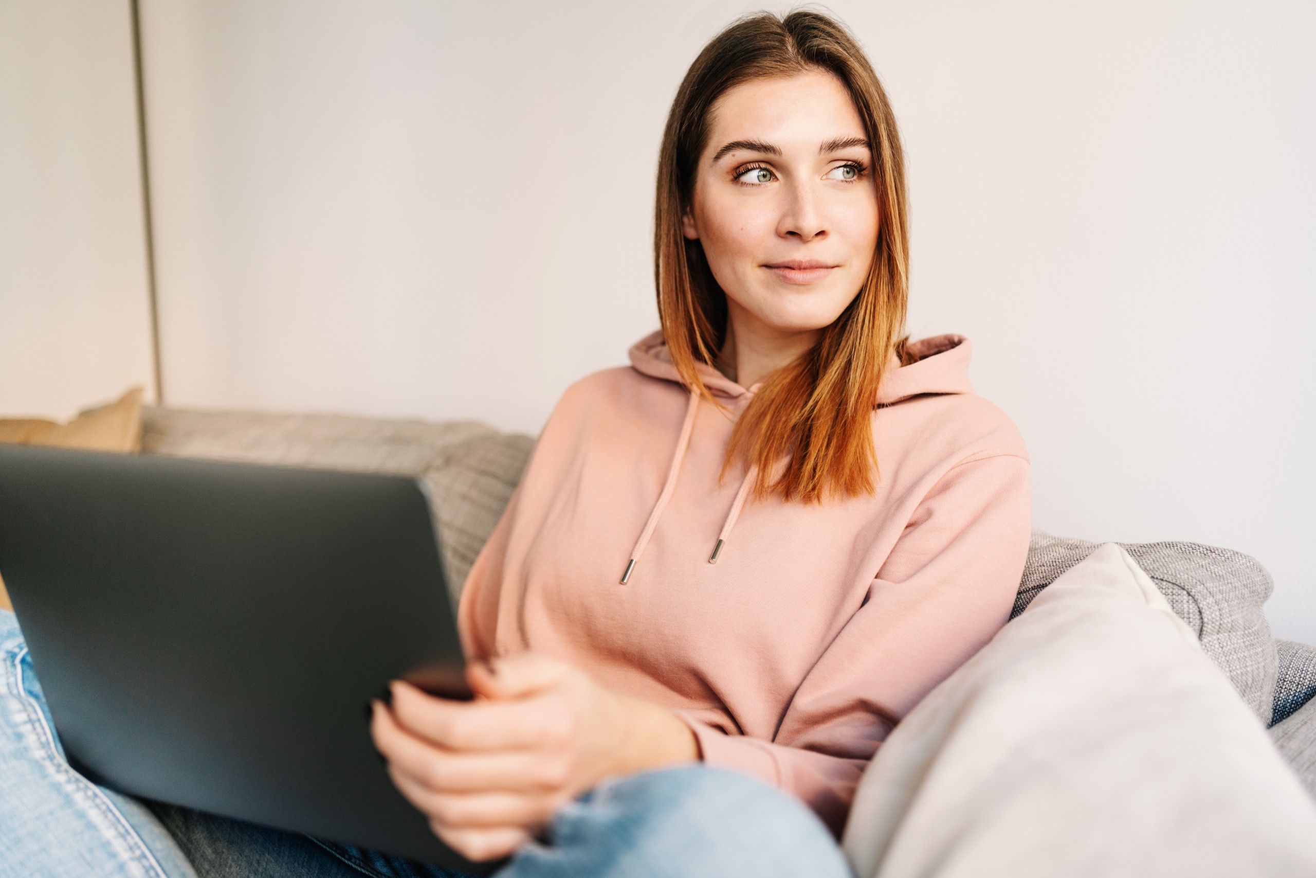 young woman sitting on her couch with her laptop searching for answers